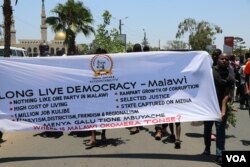 Protestors carry a banner along Kamuzu High Way In Blantyre. (Lameck Masina/VOA)
