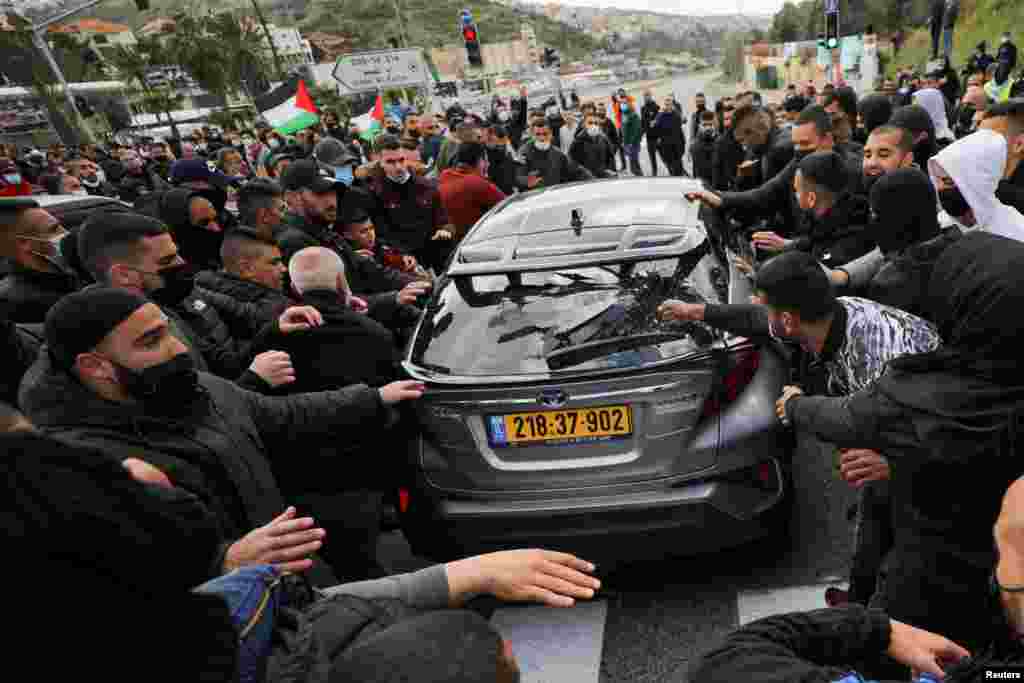 An Arab Israeli demonstrator breaks the window of a passing car during a protest against a wave of violence in their communities, where they say police have ignored crime, in northern town of Umm el Fahm, Israel.