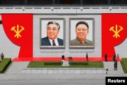 FILE - People work around pictures of former North Korean leaders Kim Il Sung, left, and Kim Jong Il at the main Kim Il Sung square in central Pyongyang, North Korea, May 7, 2016.