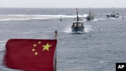 In this photo taken on Friday, July 20, 2012, Chinese fishing boats sail in the lagoon of Meiji reef off the island province of Hainan in the South China Sea.