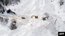 Ekskavator membersihkan salju di lokasi longsor yang menutupi rel kereta api milik perusahaan Brig Visp Zermatt Bahn antara Visp dan Taesch pada 10 Januari 2018 di dekat Sankt Niklaus, Pegunungan Alpen Swiss. (Foto: AFP)