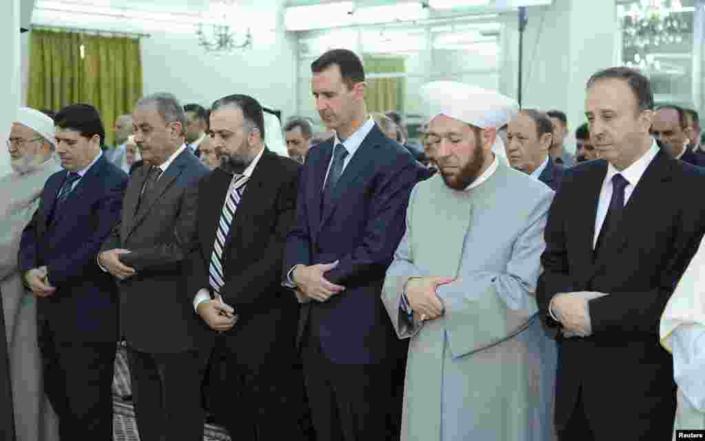 Presiden Suriah Bashar al-Assad (ketiga dari kanan) menghadiri sholat Idul Fitri di masjid Al-Hamad di Damaskus, Minggu (19/8).