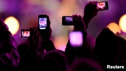 FILE - Fans take photos with their mobile phones during the VH1 "Divas Salute The Troops" show at the Marine Corps Air Station Miramar in San Diego, Dec. 3, 2010. 