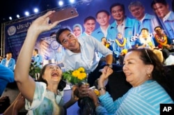 A supporter takes a selfie with the leader of Thailand's Democrat Party and candidate for prime minister, Abhisit Vejjajiva, center, during a campaign rally in Bangkok, Thailand, March 18, 2019.