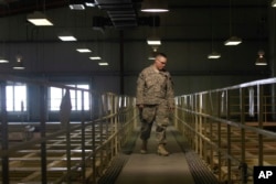 FILE - A U.S. military guard watches over detainee cells inside the Parwan detention facility near Bagram Air Field in Afghanistan, March 23, 2011. The Pentagon has denied operating secret jails in Afghanistan, although human rights groups and former detainees have described the facilities. U.S. military and other government officials confirmed that the detention centers exist but described them as temporary holding pens whose primary purpose is to gather intelligence.