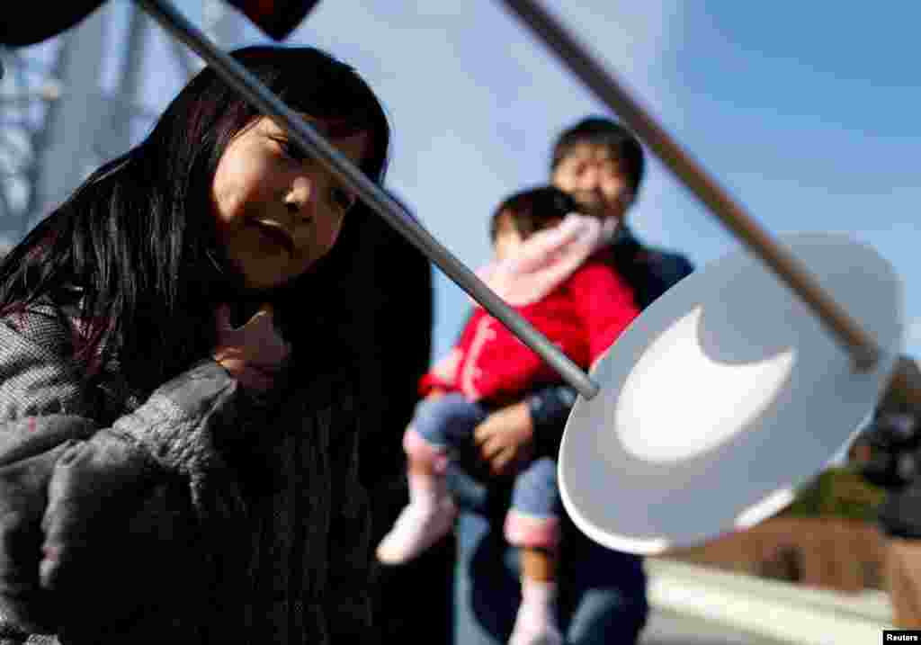 People observe a partial solar eclipse at Tokyo Skytree in Tokyo, Japan.