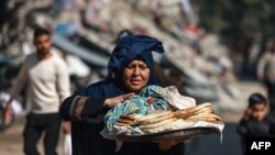 A Palestinian woman carries bread outside a UN school in Bureij in the central Gaza Strip on November 21, 2023, amid the ongoing battles between Israel and the Palestinian militant group Hamas.