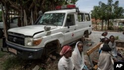 An ambulance said by residents to have been damaged and stripped for parts by Eritrean soldiers sits next to people as they wait to be seen at a medical clinic in Abi Adi, in the Tigray region of northern Ethiopia Tuesday, May 11, 2021.