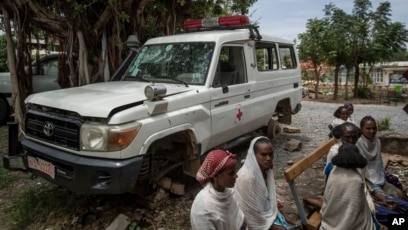 An ambulance said by residents to have been damaged and stripped for parts by Eritrean soldiers sits next to people as they wait to be seen at a medical clinic in Abi Adi, in the Tigray region of northern Ethiopia Tuesday, May 11, 2021.
