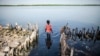 FILE - A young girl wades in the water outside of a home partially destroyed by rising sea levels in Diamniadio Island, Saloum Delta in Senegal, Oct. 18, 2015. 