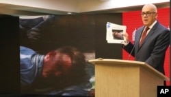 In this photo released by the Venezuelan Communications Ministry press office, Communications Minister Jorge Rodriguez shows a photograph of a man he identifies as former U.S. special forces soldier Luke Denman during his arrest, in Caracas, May 5, 2020.