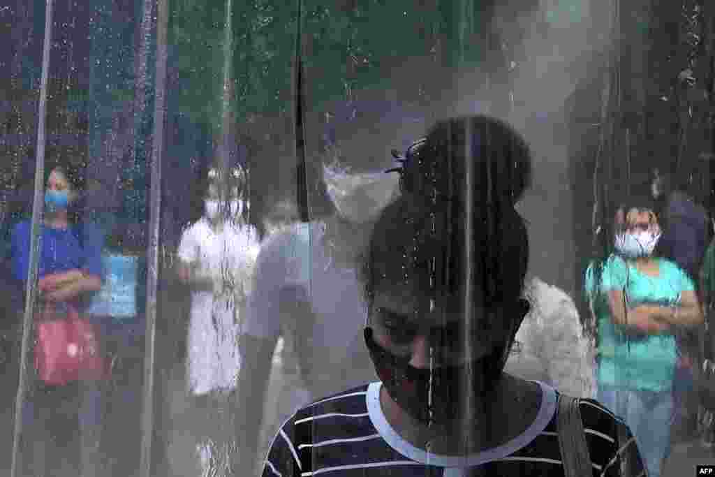 An office worker stands inside a makeshift sanitization booth before entering an office building in Colombo, Sri Lanka, as authorities eased the 24-hour curfew as a preventive measure against the spread of the COVID-19 coronavirus after 67 days. 