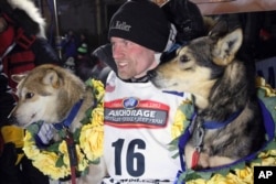 FILE - Dallas Seavey poses with his lead dogs Reef, left, and Tide after finishing the Iditarod Trail Sled Dog Race in Nome, Alaska, March 15, 2016.