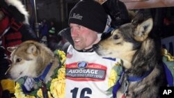 FILE - Dallas Seavey poses with his lead dogs Reef, left, and Tide after finishing the Iditarod Trail Sled Dog Race in Nome, Alaska, March 15, 2016.