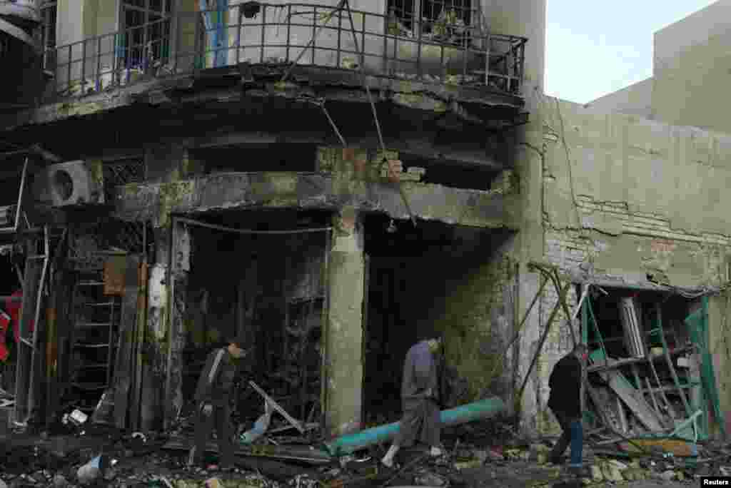 People walk past the site of bomb attacks, Karrada district, Baghdad, Feb. 18, 2014. 