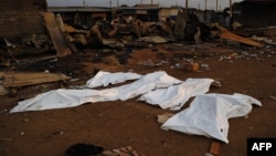 FILE - Dead bodies covered in plastic lie in front of a burnt out marketplace in Bor, South Sudan.