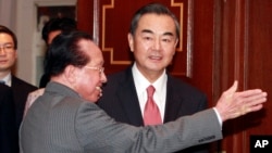 Cambodian Foreign Minister Hor Namhong, left, guides Chinese Foreign Minister Wang Yi on his arrival at a meeting room in Phnom Penh, Cambodia, Wednesday, Aug. 21, 2013. (AP Photo/Heng Sinith)