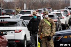 Police and U.S. Military personnel work amid a line of cars of people arriving for testing at a new drive-thru coronavirus disease (COVID-19) testing center in the Staten Island borough of New York City, New York, U.S., March 19, 2020.