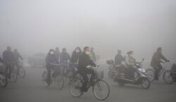FILE - People ride along a street on a smoggy day in Daqing, Heilongjiang province, China, Oct. 21, 2013.