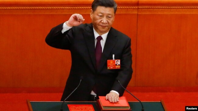 中国国家主席习近平在连任第二个任期时左手抚按宪法，右手举拳，宣誓就任。(2018年3月17日)