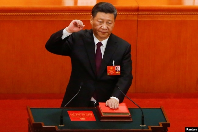 中国国家主席习近平在连任第二个任期时左手抚按宪法，右手举拳，宣誓就任。(2018年3月17日)