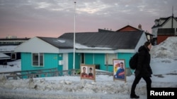 A woman walks past election campaign posters outside the polling station during general election in Nuuk, Greenland, March 11, 2025.