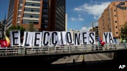 Opositores venezolanos despliegan una pancarta en una calle de Caracas, exigiendo elecciones.