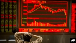 A Chinese investor monitors stock prices at a brokerage house in Beijing, Friday, Feb. 9, 2018. (AP Photo/Mark Schiefelbein)