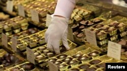 FILE - An employee takes out chocolate truffles at a shop.