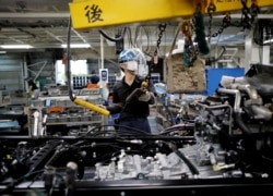 FILE - An employee wearing a protective face mask and face guard works on the automobile assembly line at Kawasaki factory of Mitsubishi Fuso Truck and Bus Corp, owned by Germany-based Daimler AG, in Kawasaki, south of Tokyo, Japan May 18, 2020. (REUTERS)