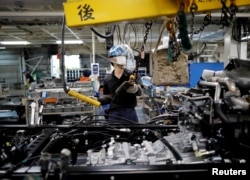 FILE - An employee wearing a protective face mask and face guard works on the automobile assembly line at Kawasaki factory of Mitsubishi Fuso Truck and Bus Corp, owned by Germany-based Daimler AG, in Kawasaki, south of Tokyo, Japan May 18, 2020. (REUTERS)