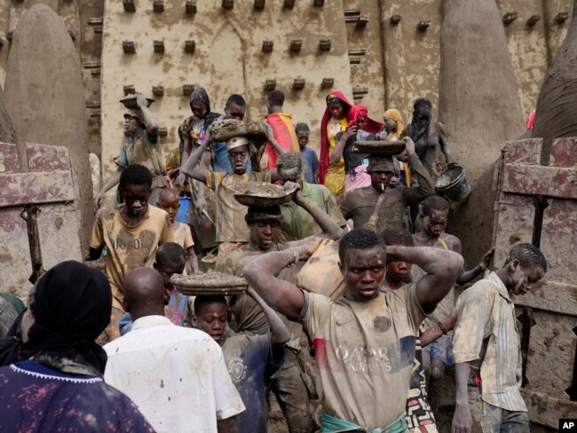 Malians take part in the annual replastering of the world's largest mud-brick building, the Great Mosque of Djenne, Mali, Sunday, May 12, 2024. (AP Photo/Moustapha Diallo)