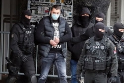 Serbian police officers escort detained Partizan fan leader Veljko Belivuk, 2nd left, during a raid on the Partizan stadium in Belgrade, Feb. 4, 2021.