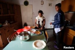 FILE - Eritrean migrants prepare food in their home in Riace, Calabria region, Italy, Nov. 21, 2013.