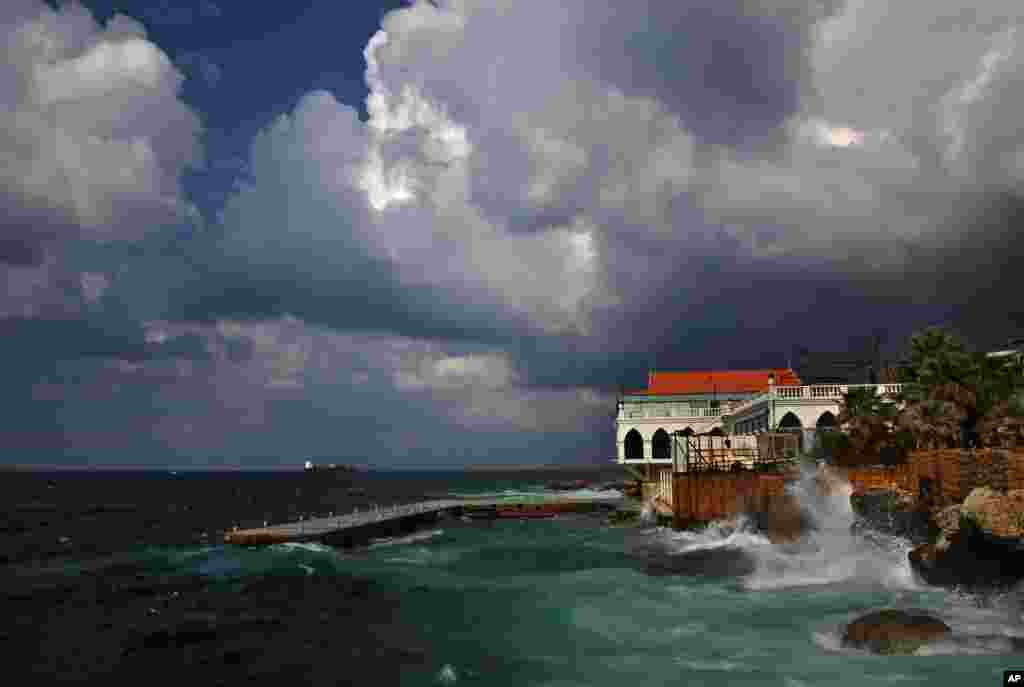 Waves crash on the seawall of a restaurant while clouds darken the sky over the Lebanese capital Beirut.