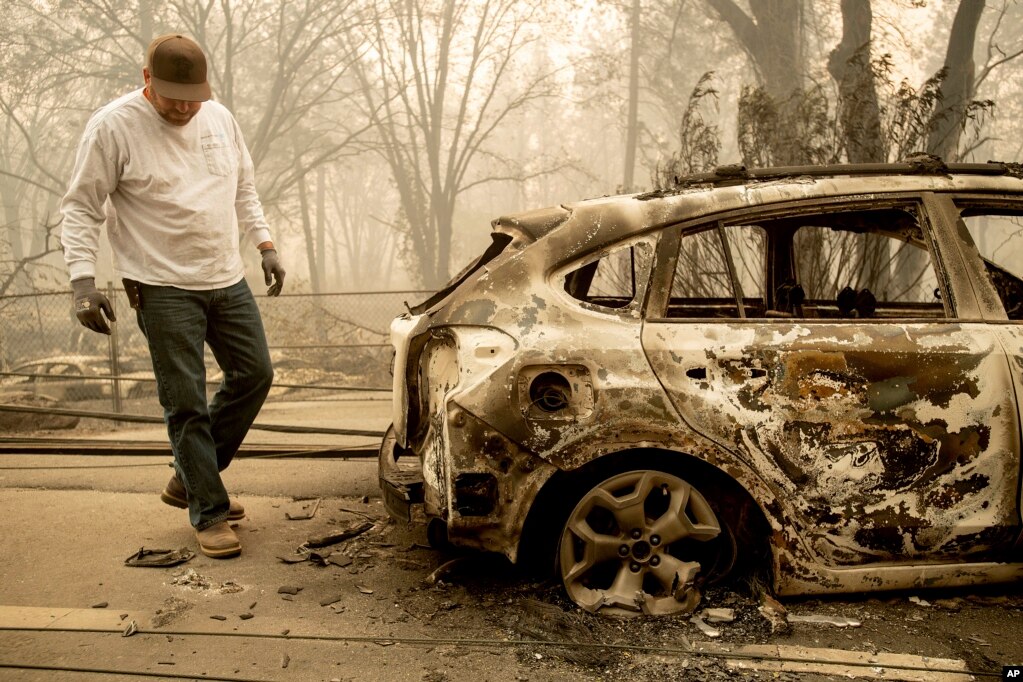 Eric England searches through a friend's vehicle on Pearson Rd. after the wildfire burned through Paradise, Calif., Nov. 10, 2018. Not much is left in Paradise after a ferocious wildfire roared through the Northern California town as residents fled and entire neighborhoods are leveled.