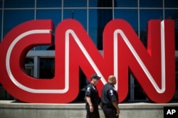 FILE - Security guards walk past the entrance to CNN headquarters, Aug. 26, 2014, in Atlanta, Georgia.