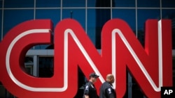 Security guards walk past the entrance to CNN headquarters, Aug. 26, 2014, in Atlanta, Georgia. 