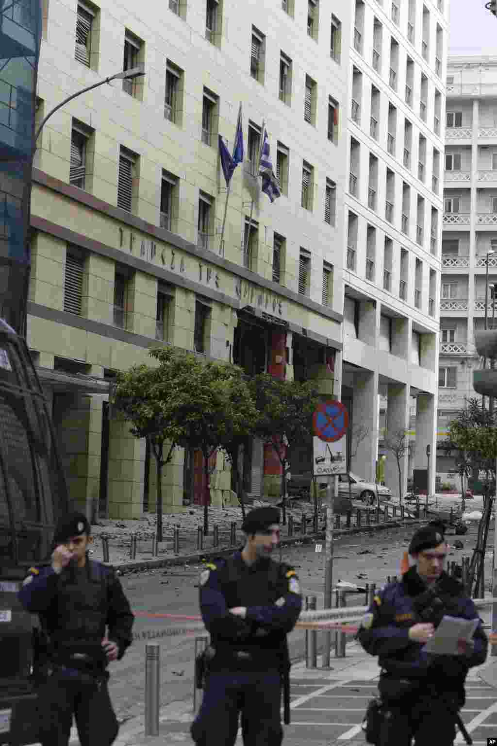 Police officers block the way to the damaged entrance of a building after a car bomb explosion in central Athens, April 10, 2014. 