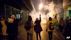 In this photograph taken Saturday, Jan. 11, 2020, protesters hold flowers as tear gas fired by police rises at a demonstration in front of Amir Kabir University in Tehran, Iran, to remember victims of a Ukrainian airplane shot down by an Iranian missile.