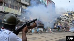 A police personnel fires tear gas shells to disperse activists marching towards the state secretariat demanding the resignation of Mamata Banerjee, chief minister of India's West Bengal state in Kolkata on August 27, 2024.