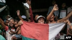 FILE —Supporters of members of the collective of opposition candidates wave the national flag of Madagascar flag as they march through the streets of Itaosy district to protest against the holding of the 2023 Presidential Election, in Antananarivo, on November 13, 2023. 