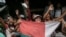 FILE —Supporters of members of the collective of opposition candidates wave the national flag of Madagascar flag as they march through the streets of Itaosy district to protest against the holding of the 2023 Presidential Election, in Antananarivo, on November 13, 2023. 