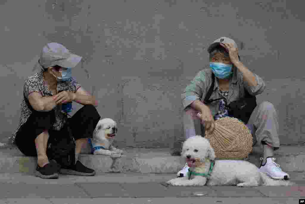 중국 베이징에서 두 여성이 마스크를 착용한 채 도로변에 앉아 담소를 나누고 있다. 
