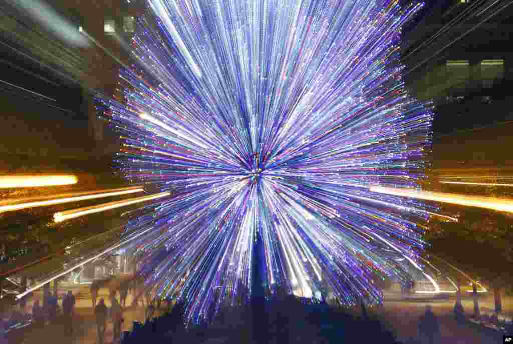 Tourists walk past the Millennium Park Christmas tree in a timed exposure with a zoom lens, in Chicago, Illinois, Nov. 30, 2016.