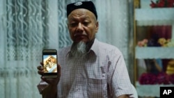 Ablikim Abliz holds up his phone with a photo of his uncle's family with an unknown Han Chinese man in Istanbul, Turkey, Aug. 22, 2018. He later heard that his uncle's front door was boarded up and sealed with police tape, and has not been able to contact him since.