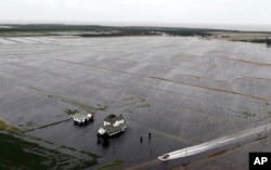 Una camioneta cruza una carretera inundada cerca de una casa rodeada por campos inundados de la tormenta tropical Florence en Hyde County, Carolina del Norte, el sábado 15 de septiembre de 2018. (AP Photo / Steve Helber)