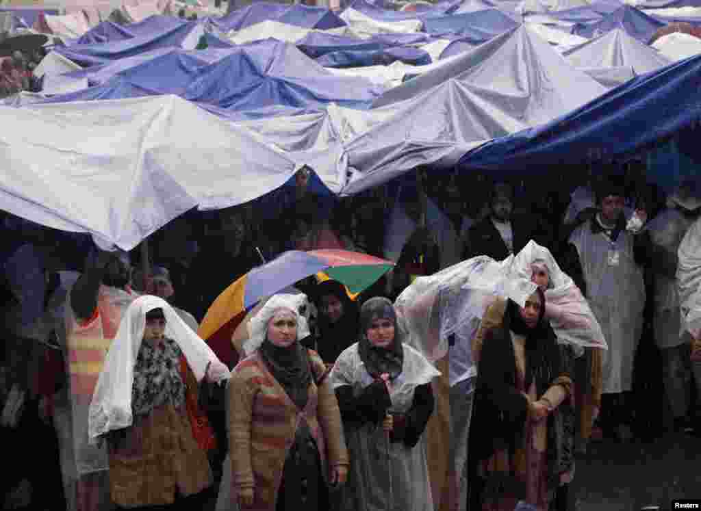 Supporters of Tahir-ul Qadri listen to him while standing in the rain during the fourth day of protest in Islamabad, Pakistan, January 17, 2013. 