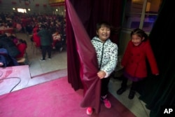 Chinese girls react as they hide from their friends during a "1,000 people dumpling feast" held on Chinese New Year's eve in Liuminying, Jan. 27, 2017.