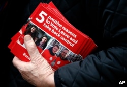 FILE - A Pro-Brexit campaigner hands out leaflets at Liverpool Street station in London.